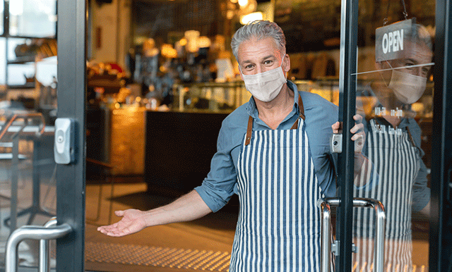 man in medical mask holding door open