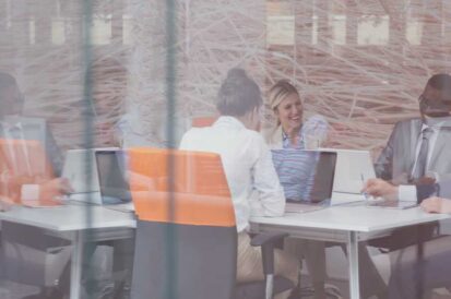 People sitting at a table with ther laptops conducting business