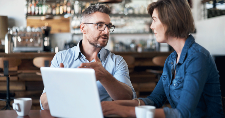 two people talking in a café at a laptop