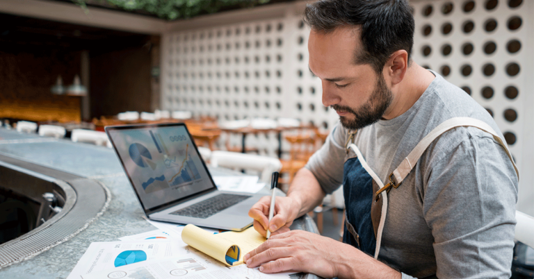 A person writing down information from his computer